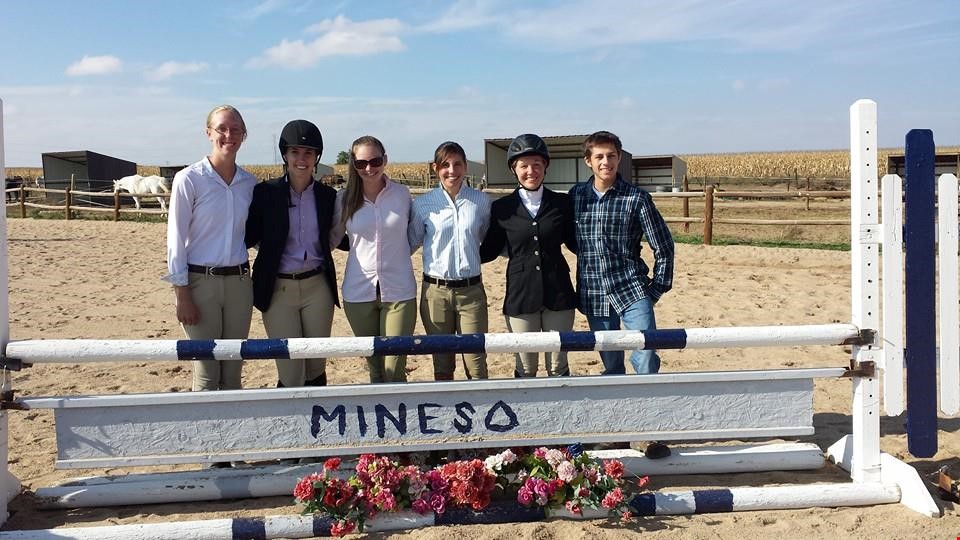 6 past members of the equestrian team behind a jump with mines painted along the rail
